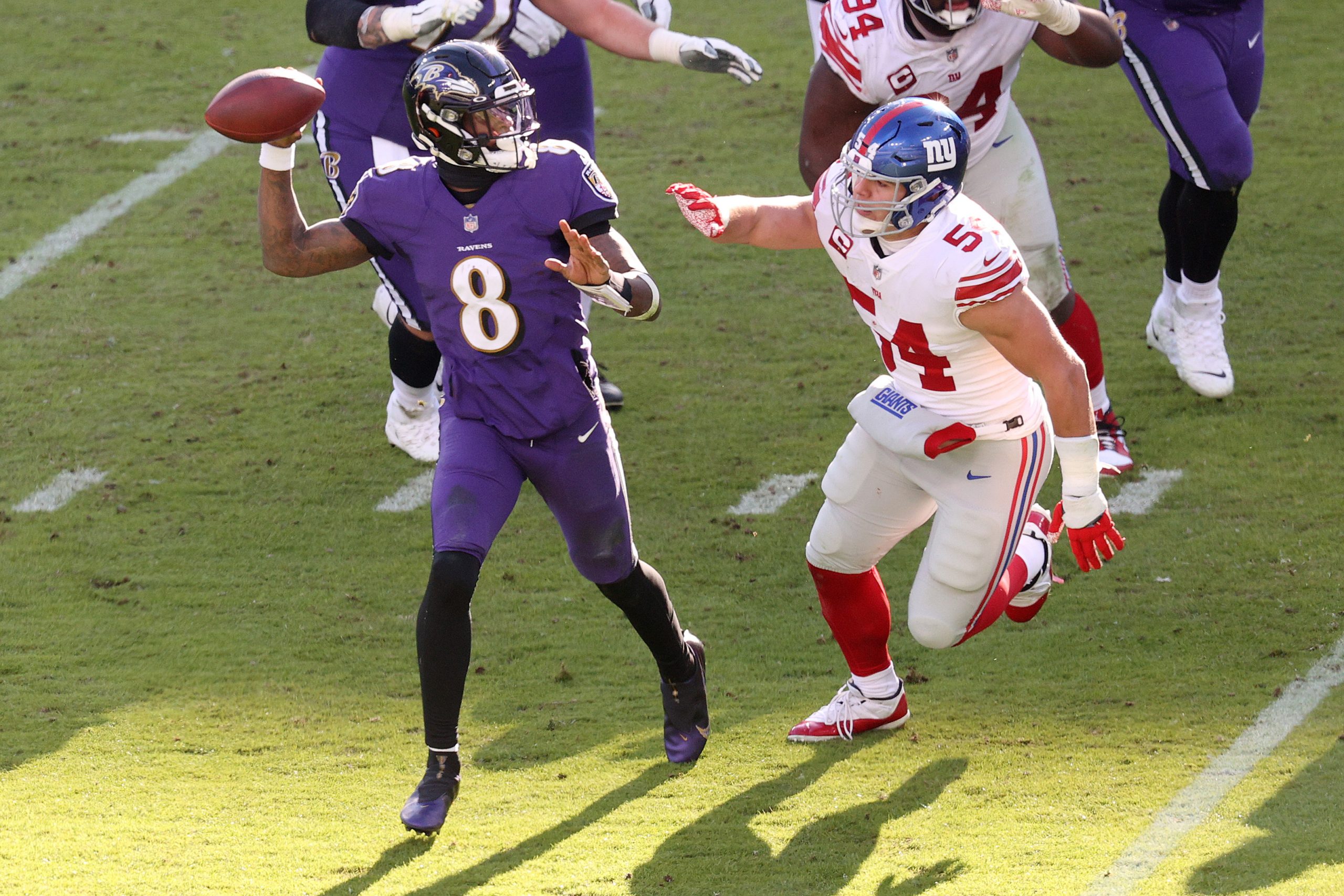 Quarterback Lamar Jackson #8 of the Baltimore Ravens passes under pressure from inside linebacker B...