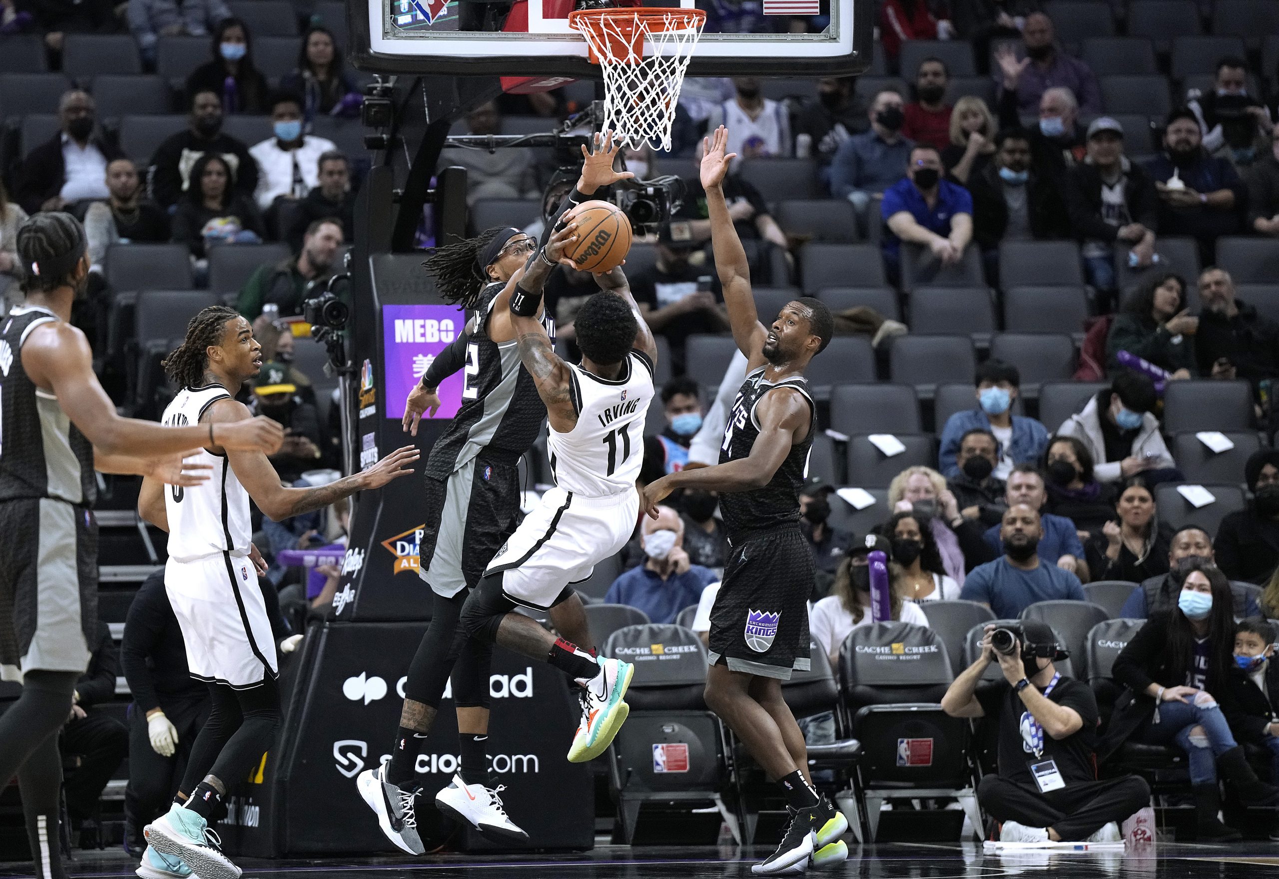Kyrie Irving #11 of the Brooklyn Nets shoots and scores over Harrison Barnes #40 and Richaun Holmes...