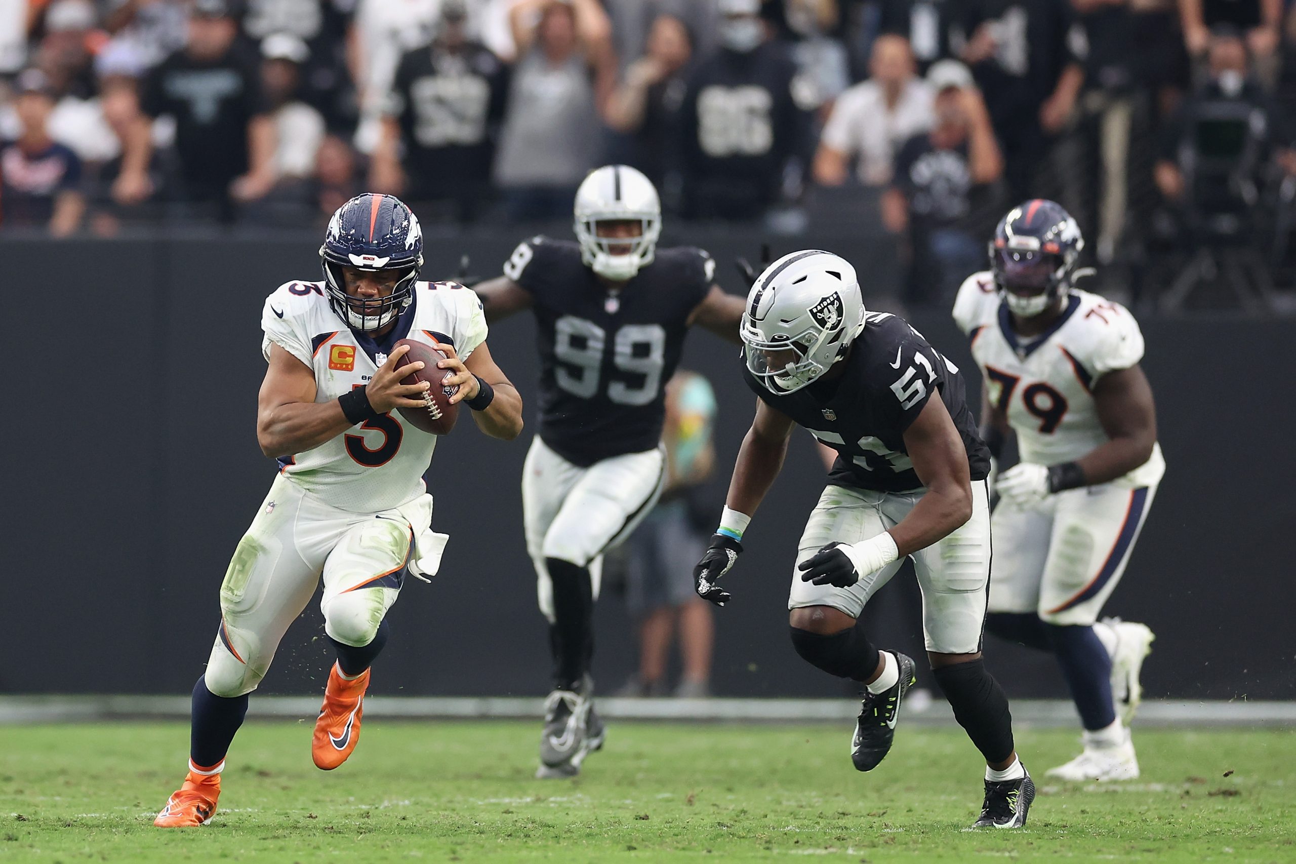 Quarterback Russell Wilson #3 of the Denver Broncos rushes the football past defensive end Malcolm ...