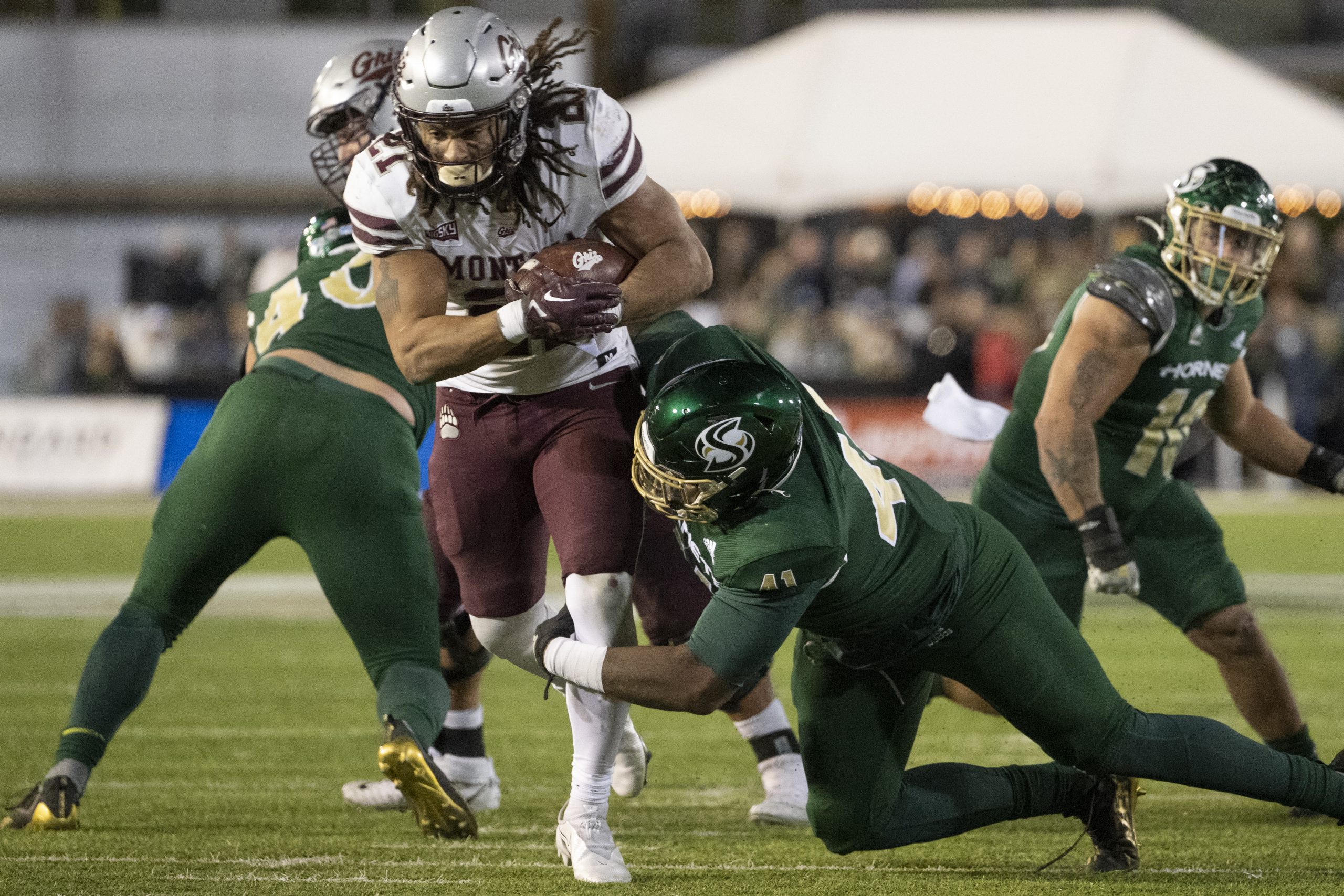 Marcus Knight #21 of the Montana Grizzlies runs with the ball as he gets tackled by DeShawn Lynch #...