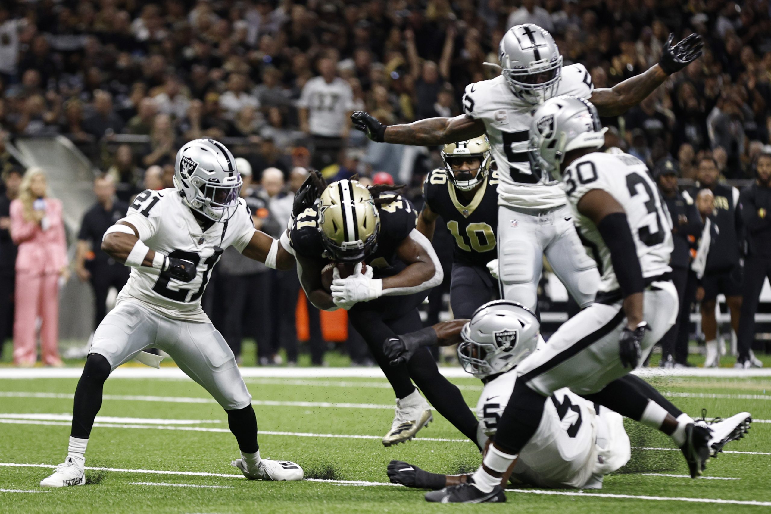Alvin Kamara #41 of the New Orleans Saints runs with the ball as a pack of Las Vegas Raiders look t...