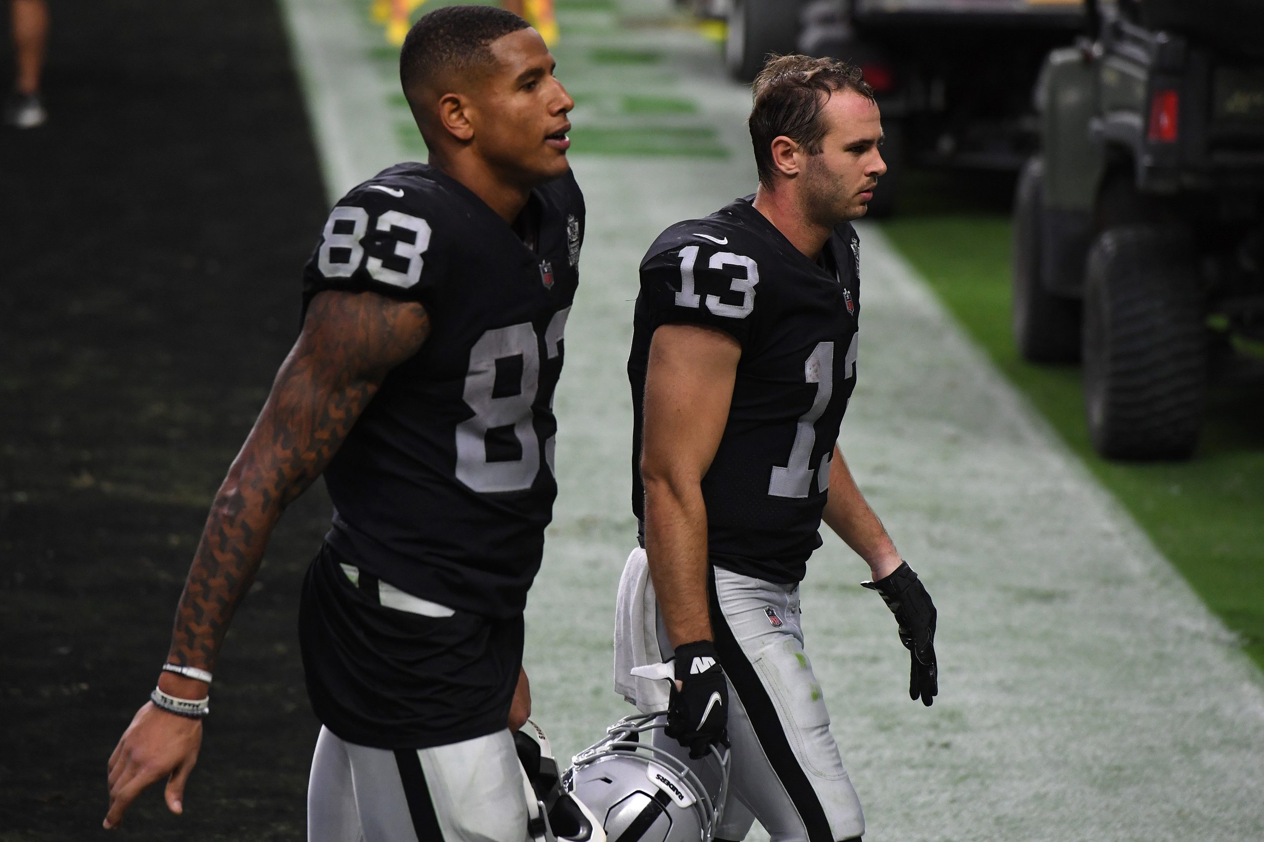 Darren Waller #83 and Hunter Renfrow #13 of the Las Vegas Raiders walk off the field after the team...