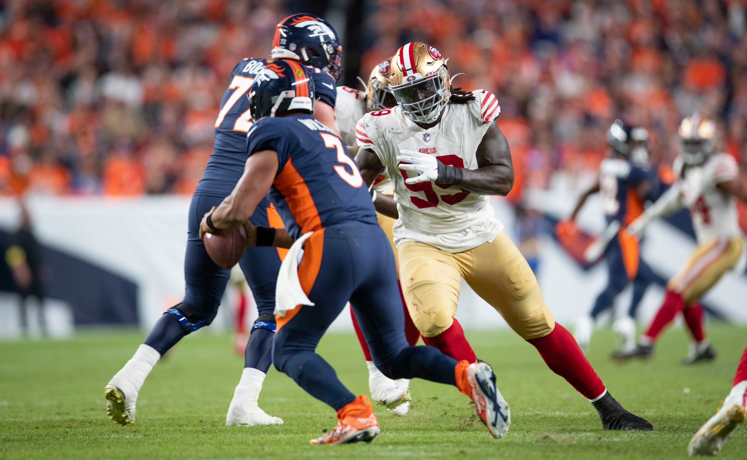 Russell Wilson #3 of the Denver Broncos avoids Javon Kinlaw #99 of the San Francisco 49ers during t...