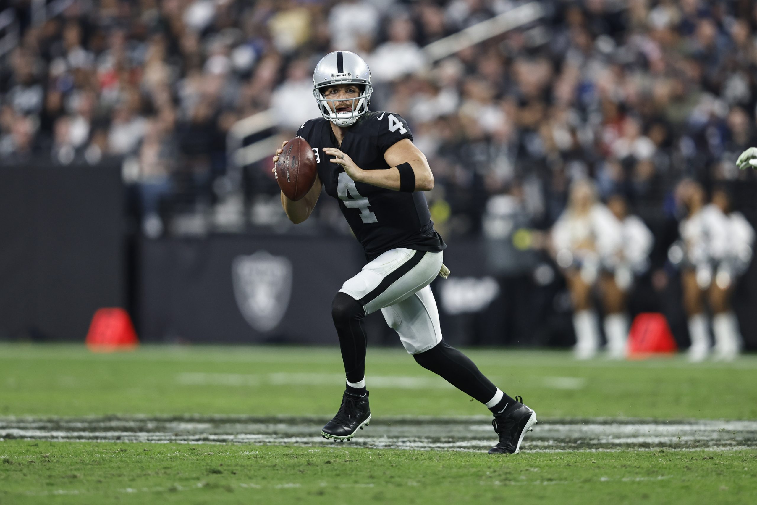 Derek Carr #4 of the Las Vegas Raiders scrambles and looks to pass during an NFL game between the L...