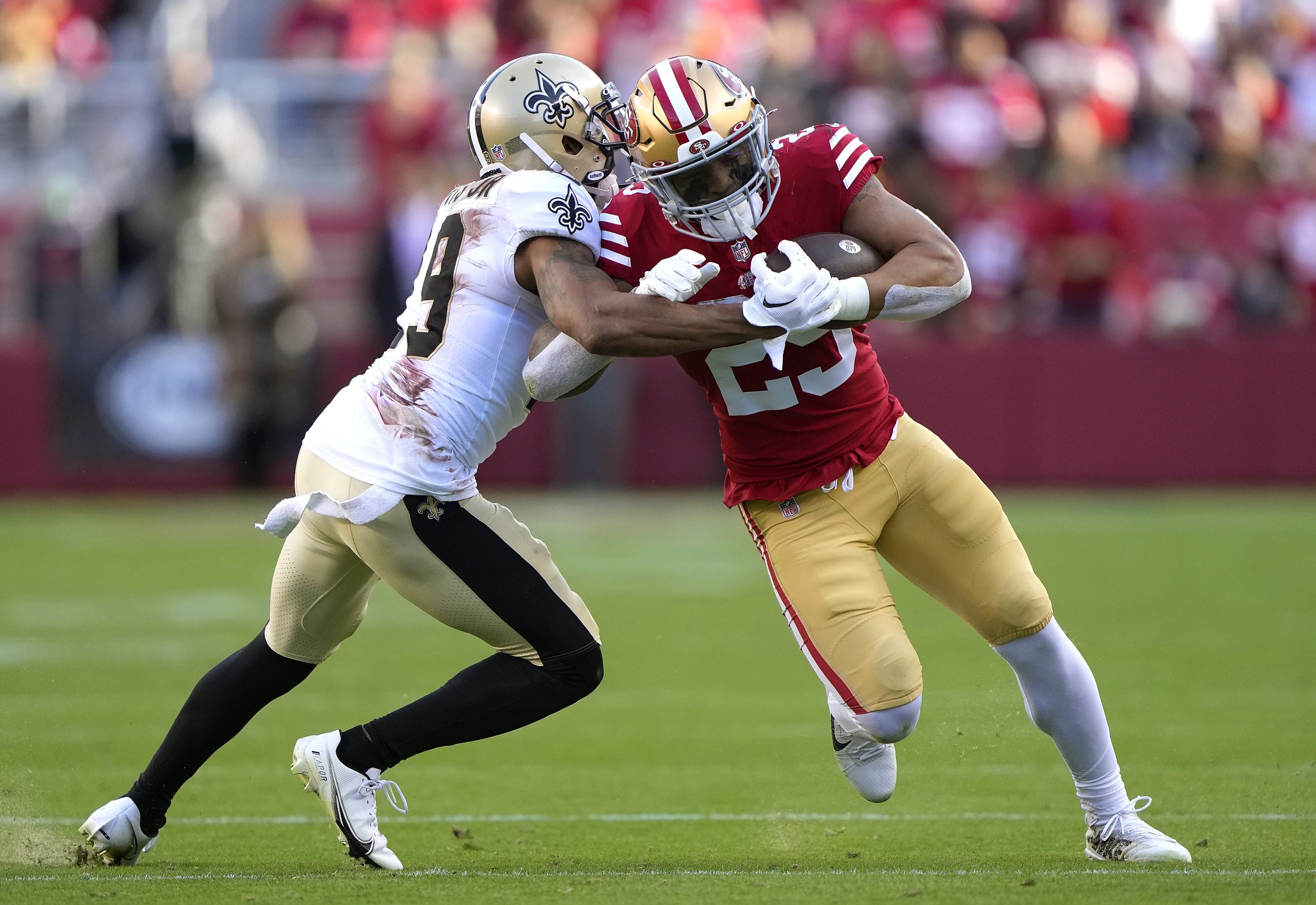 Elijah Mitchell #25 of the San Francisco 49ers fights off the tackle of Chris Harris Jr. #19 of the...