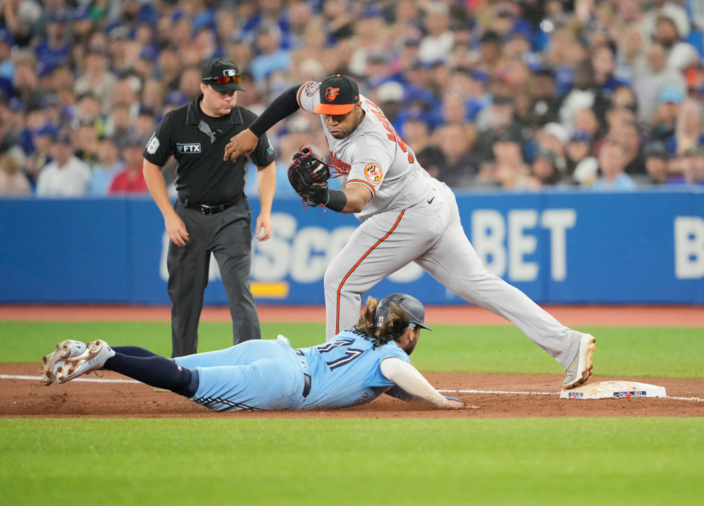 Jesus Aguilar #99 of the Baltimore Orioles records the last out of a triple play on Bo Bichette #11...