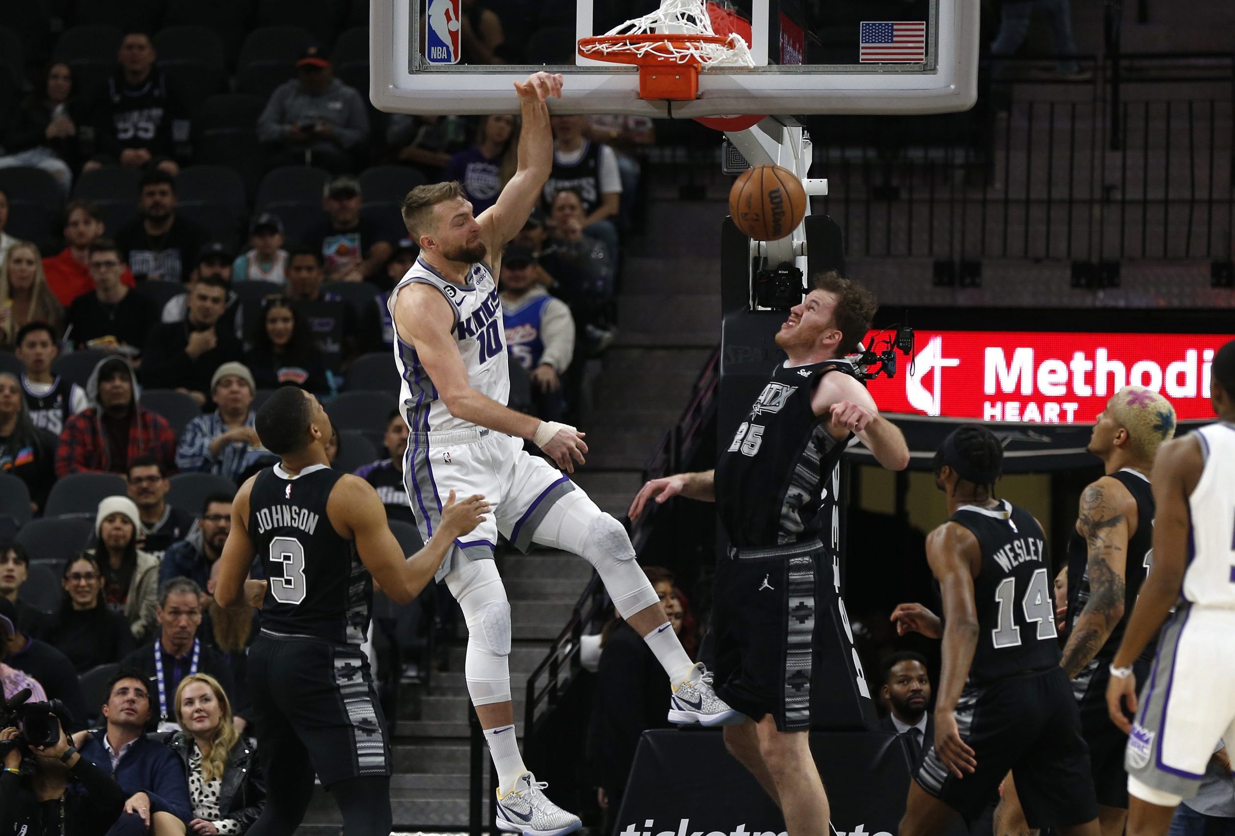 Domantas Sabonis #10 of the Sacramento Kings dunks over Jakob Poeltl #25 of the San Antonio Spurs i...