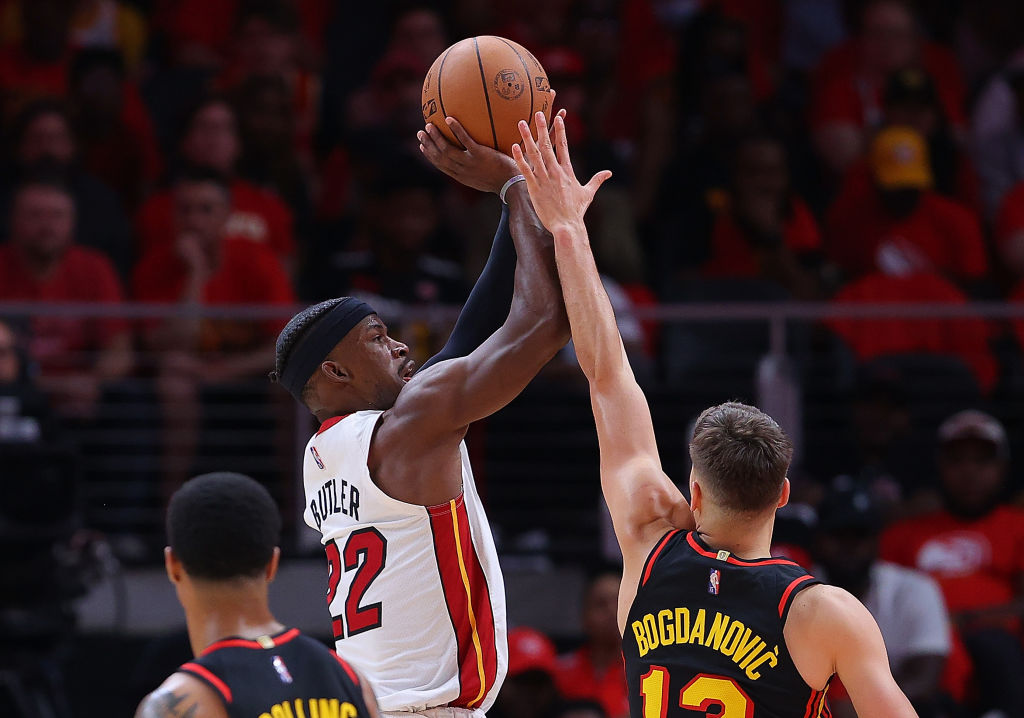Jimmy Butler #22 of the Miami Heat attempts a shot against Bogdan Bogdanovic #13 of the Atlanta Haw...