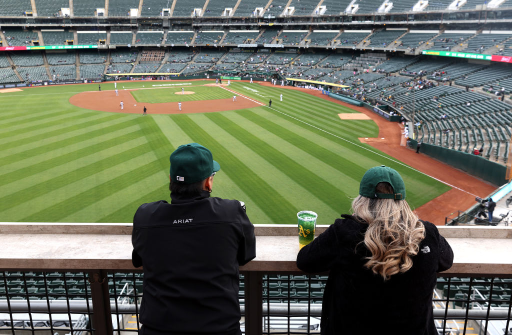 Two baseball fans watch the Oakland A's play the Texas Rangers in front of a small crowd at RingCen...