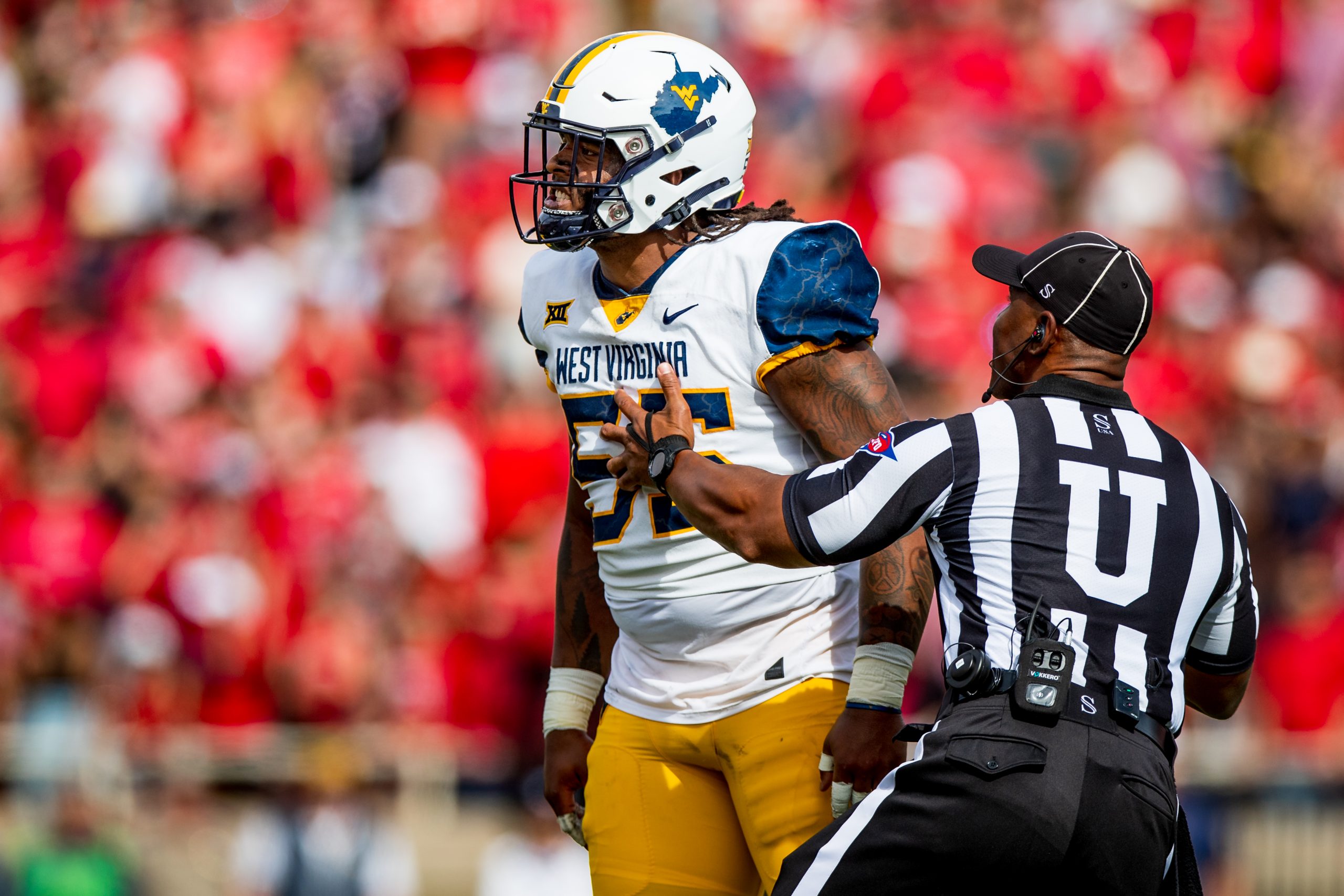 Defensive lineman Dante Stills #55 of the West Virginia Mountaineers is restrained by umpire Sheldo...