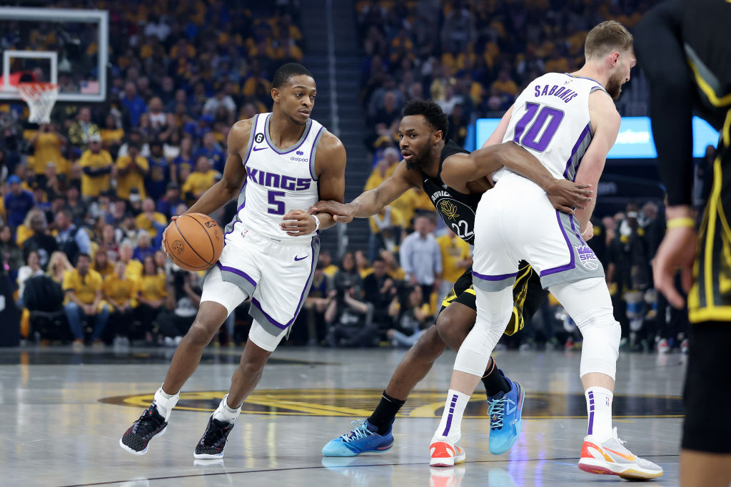 De'Aaron Fox #5 of the Sacramento Kings is guarded by Andrew Wiggins #22 of the Golden State Warrio...