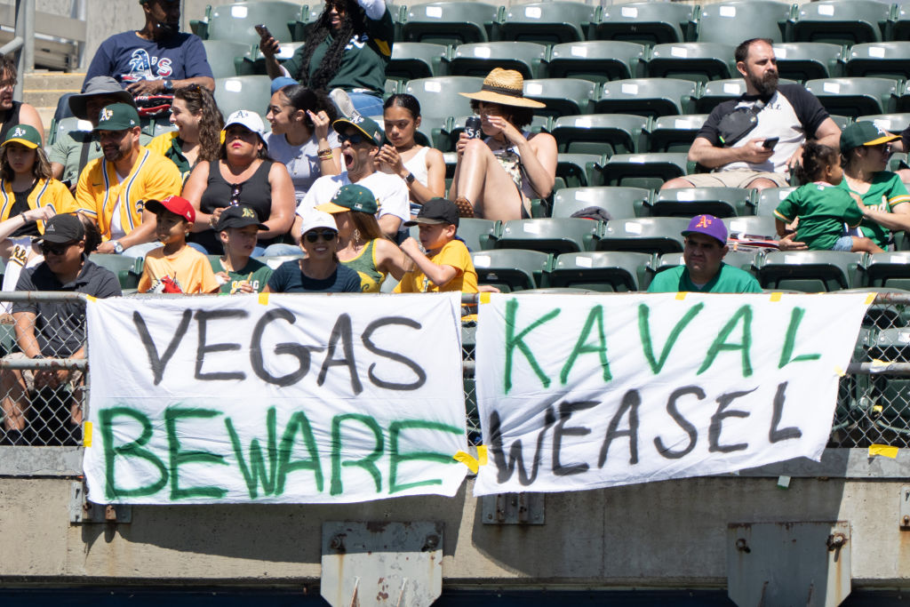 Oakland Athletics fans sit behind signs during the sixth inning against the Texas Rangers at RingCe...