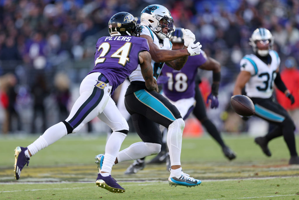 Marcus Peters #24 of the Baltimore Ravens breaks up a pass intended for DJ Moore #2 of the Carolina...