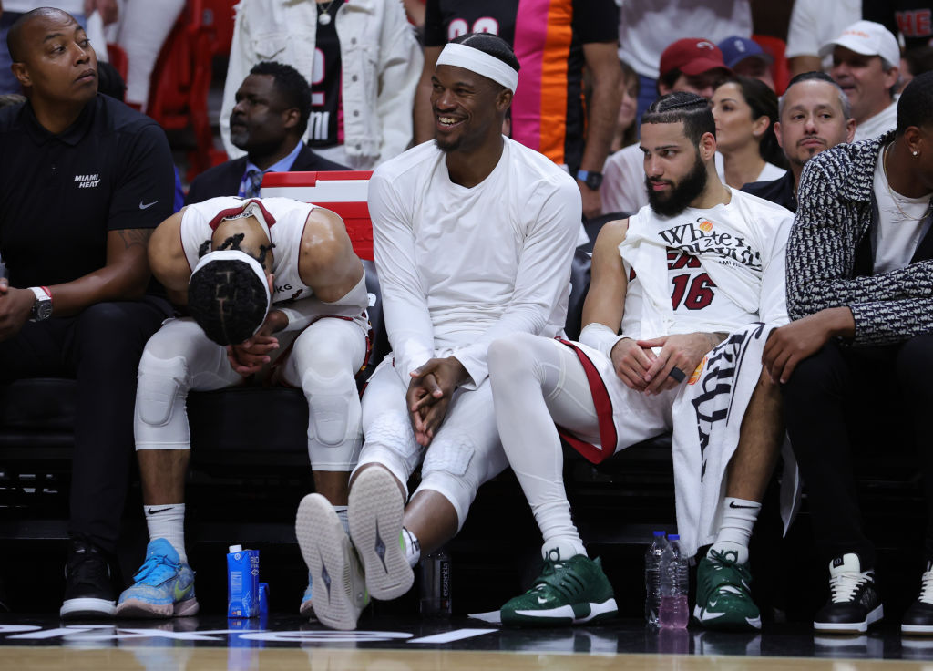 Gabe Vincent #2, Caleb Martin #16, and Jimmy Butler #22 of the Miami Heat are seen on the bench dur...