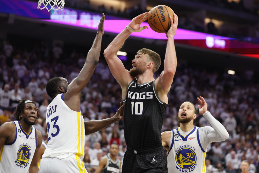 Domantas Sabonis #10 of the Sacramento Kings drives to the basket against Draymond Green #23 of the...