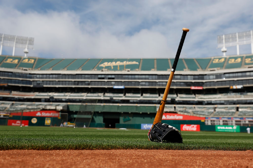OAKLAND, CALIFORNIA - JUNE 27: A glove and bat sit on the field before the game between the Oakland...