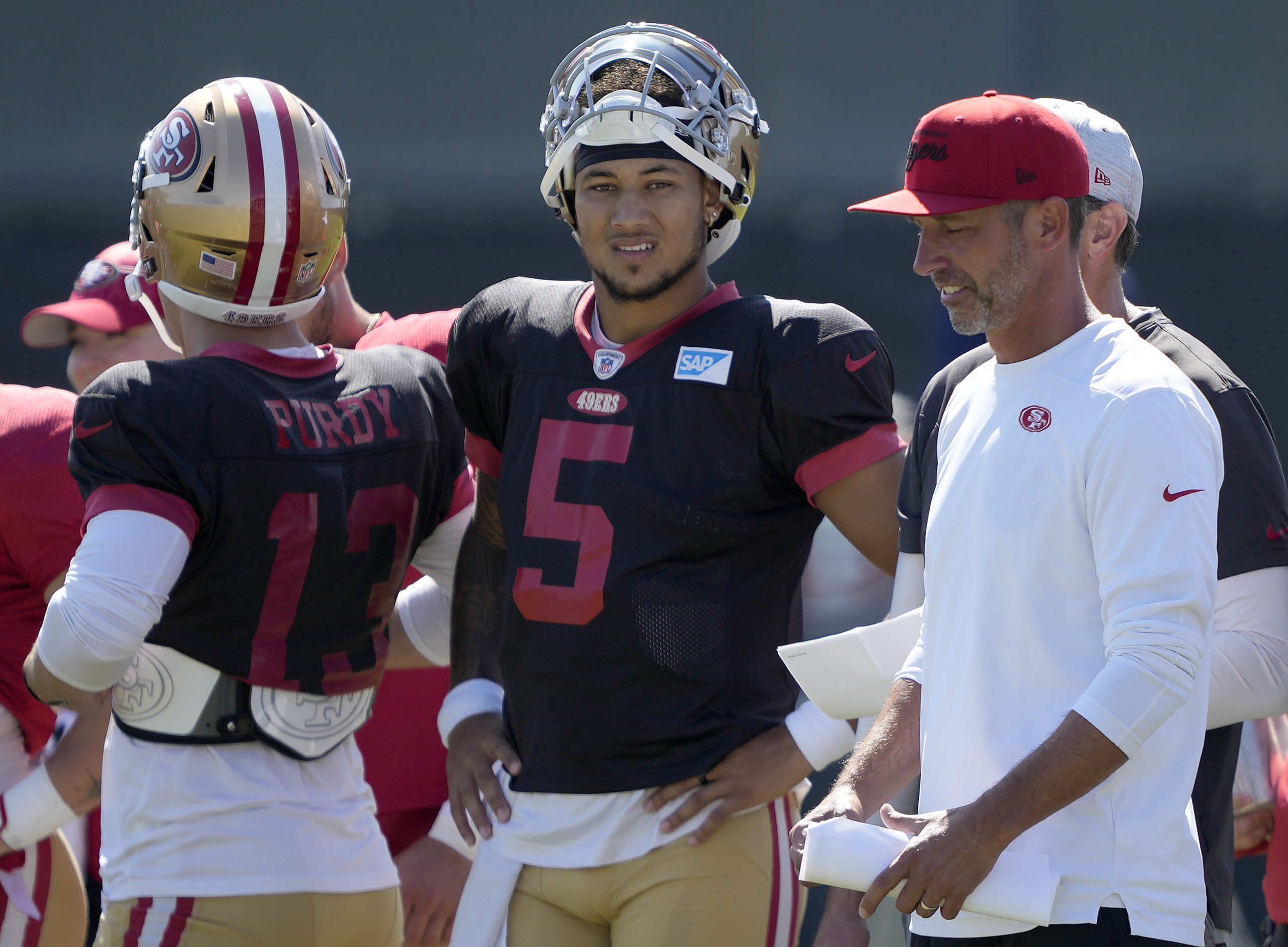 Head coach Kyle Shanahan of the San Francisco 49ers talks with his quarterbacks Trey Lance #5 and B...