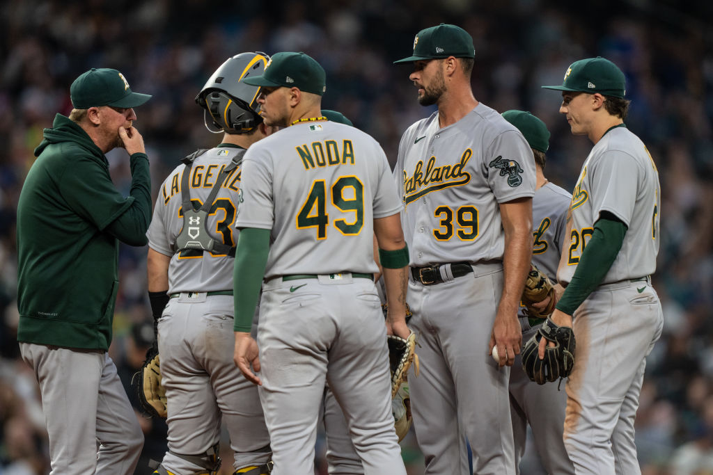 Starting pitcher Kyle Muller #39 of the Oakland Athletics meets at the mound with pitching coach Sc...