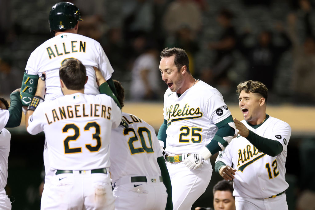 Brent Rooker #25 of the Oakland Athletics is congratulated by teammates after he hit a two-run home...