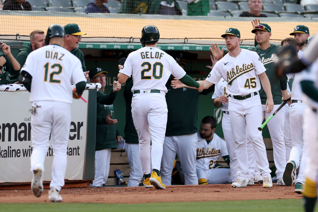 Zack Gelof #20 of the Oakland Athletics is congratulated by teammates after he scored against the K...