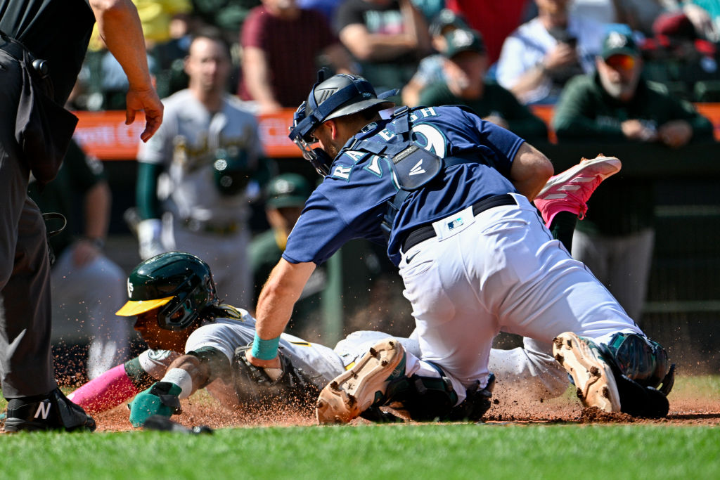 Esteury Ruiz #1 of the Oakland Athletics is tagged out at home plate by Cal Raleigh #29 of the Seat...
