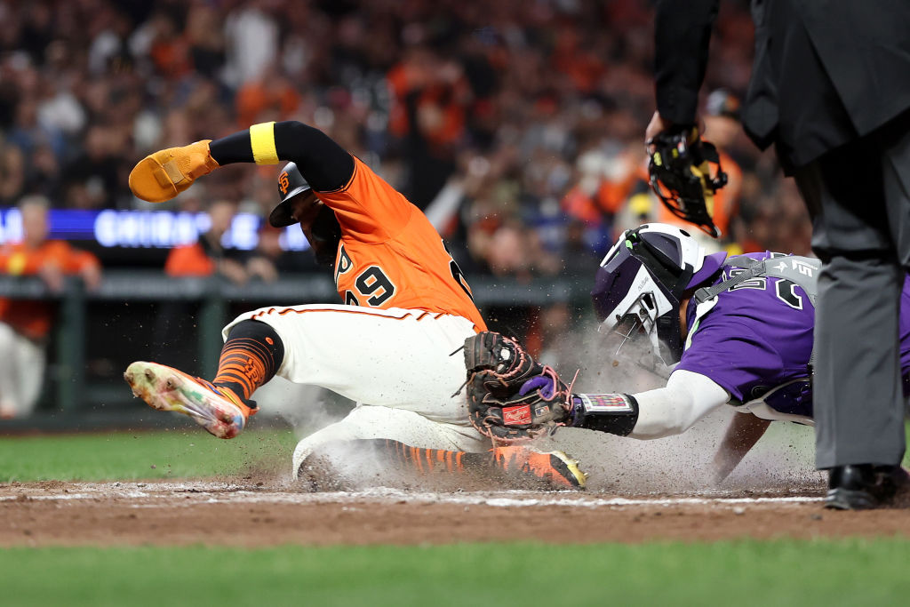 Luis Matos #29 of the San Francisco Giants is tagged out by Elias Diaz #35 of the Colorado Rockies ...