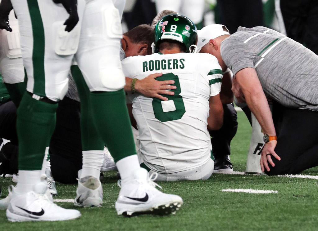 Quarterback Aaron Rodgers #8 of the New York Jets is attended to after being sacked by Leonard Floy...