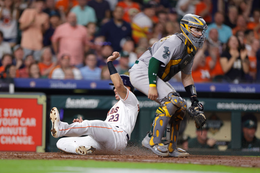 Michael Brantley #23 of the Houston Astros scores ahead of Shea Langeliers #23 of the Oakland Athle...