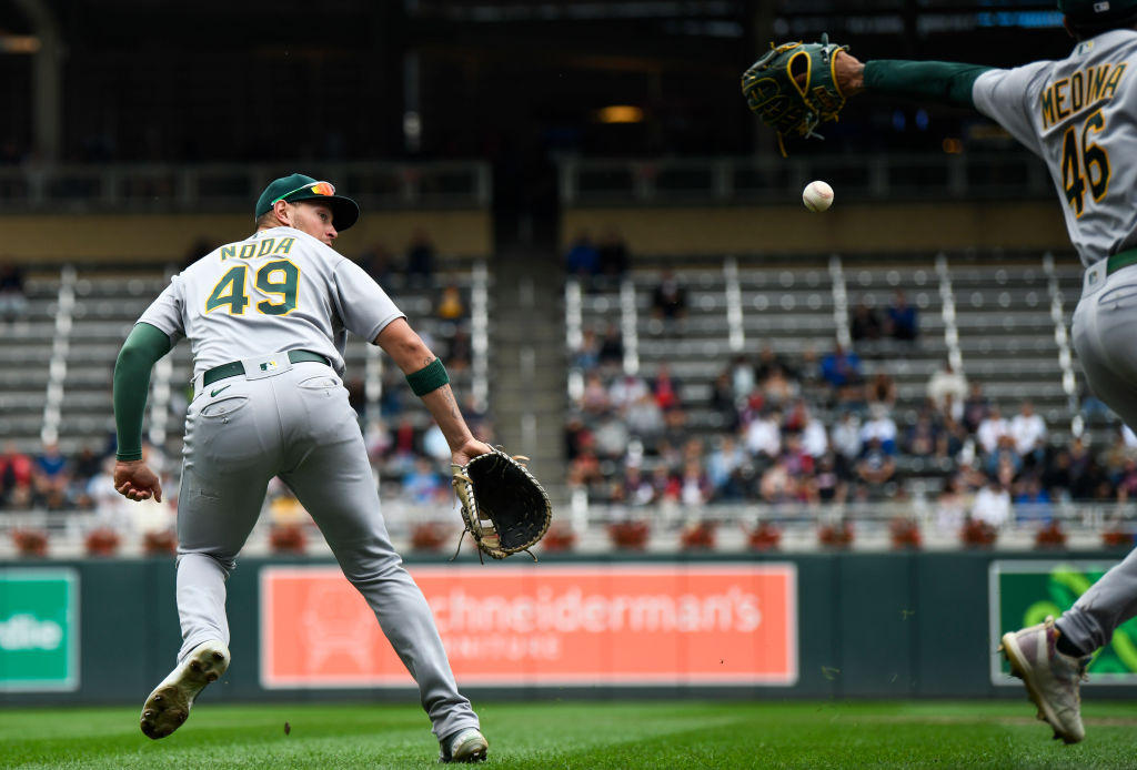 Ryan Noda #49 of the Oakland Athletics attempts to backhand the ball to first base on a play in the...