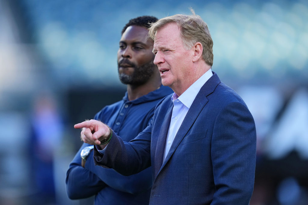 Former NFL quarterback Michael Vick stands with NFL Commissioner Roger Goodell before the game betw...