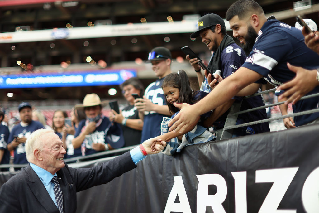 Owner Jerry Jones of the Dallas Cowboys greets fans as he walks onto the field before the NFL game ...