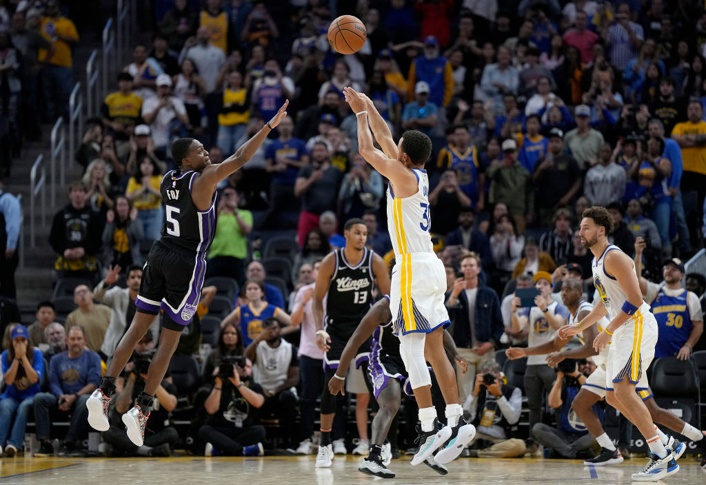Steph Curry #30 of the Golden State Warriors shoots and makes a three-point shot over De'Aaron Fox ...