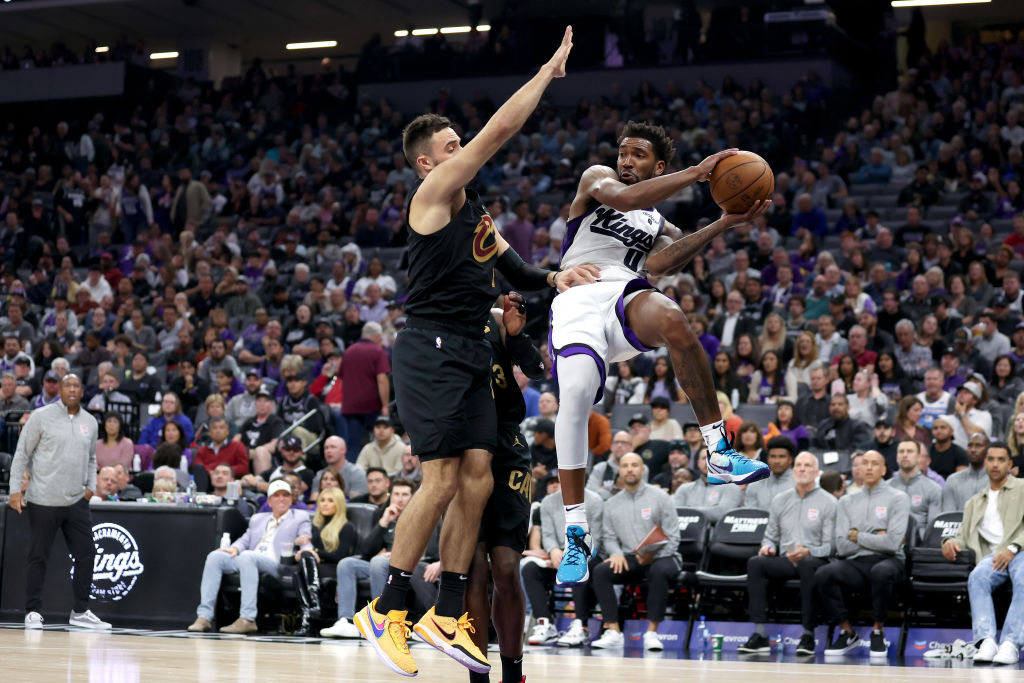Malik Monk #0 of the Sacramento Kings looks to pass around Max Strus #1 of the Cleveland Cavaliers ...