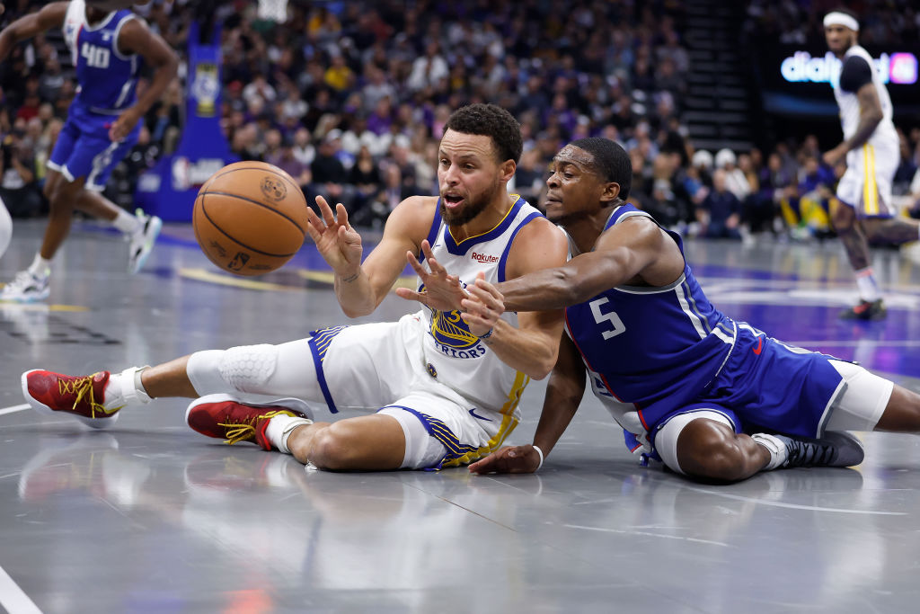 Stephen Curry #30 of the Golden State Warriors competes for a loose ball against De'Aaron Fox #5 of...
