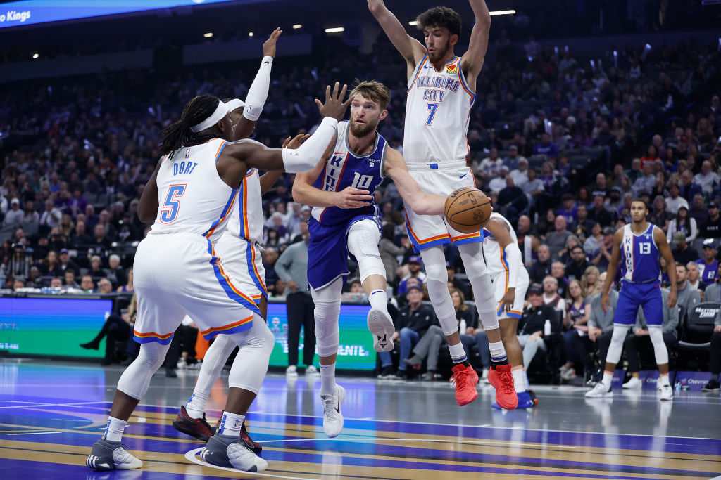 Domantas Sabonis #10 of the Sacramento Kings passes the ball against Luguentz Dort #5 and Chet Holm...