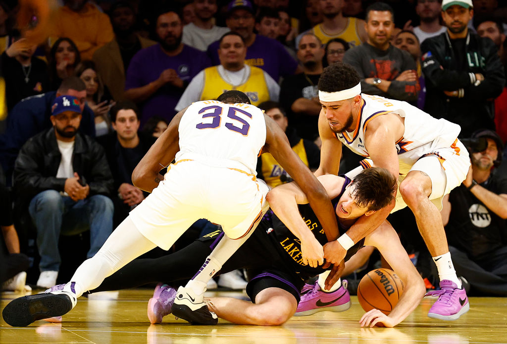 Austin Reaves #15 of the Los Angeles Lakers is defended by Kevin Durant #35 and Devin Booker #1 of ...