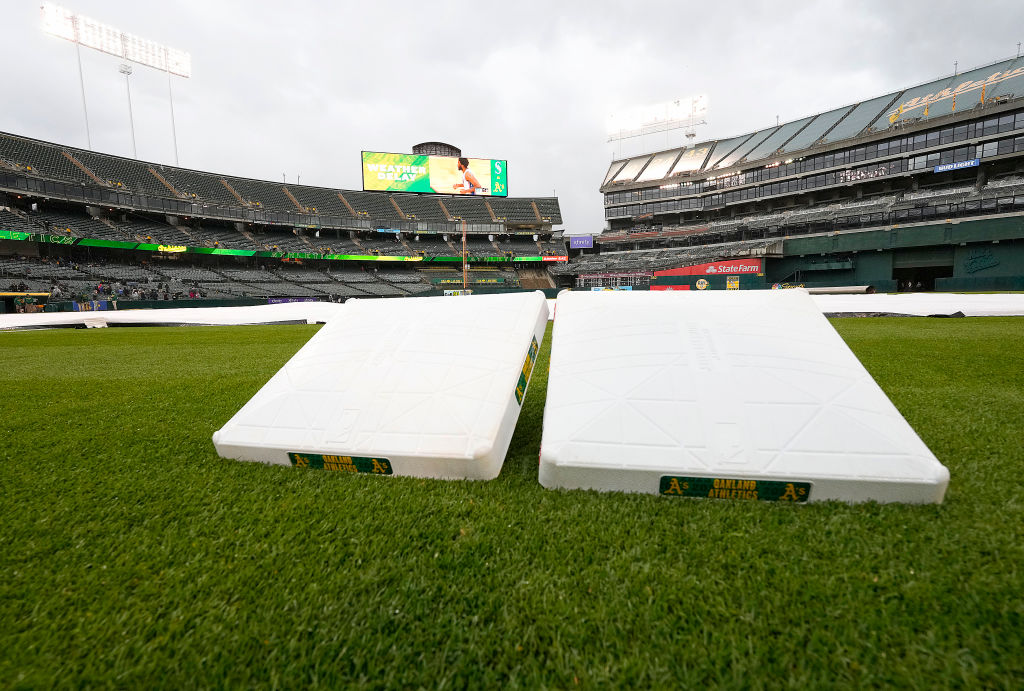 A detailed view of the bases set to the side while the tarp is stretched across the infield during ...