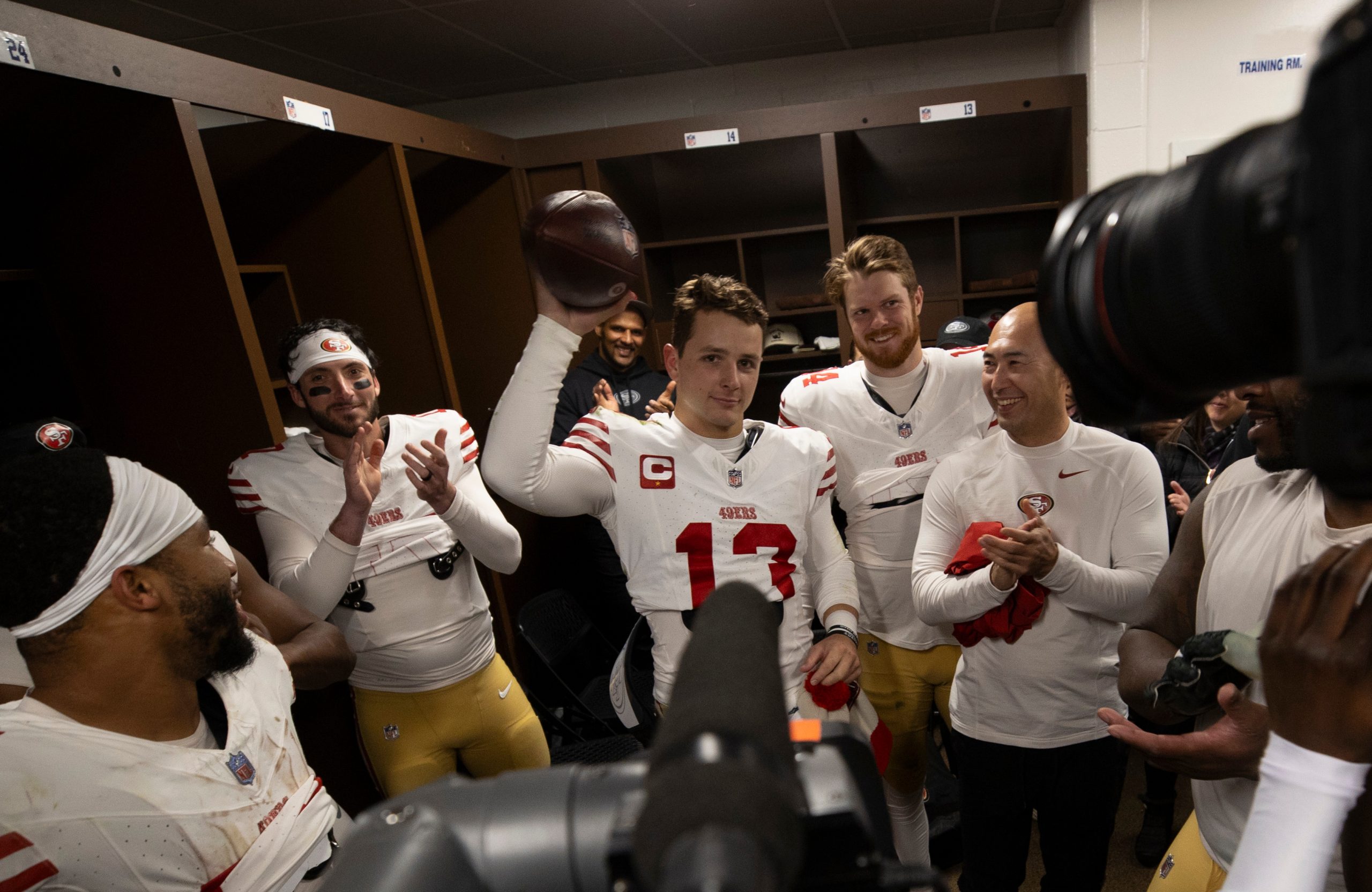Brock Purdy #13 of the San Francisco 49ers with the game ball in the locker room after the game aga...