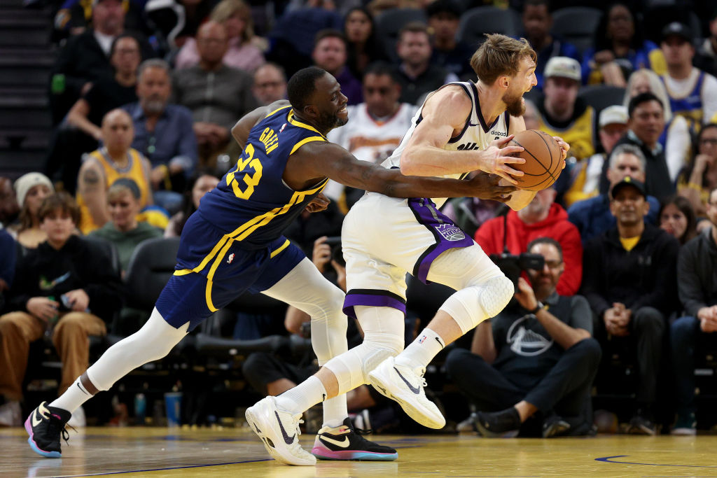 Domantas Sabonis #10 of the Sacramento Kings is guarded by Draymond Green #23 of the Golden State W...