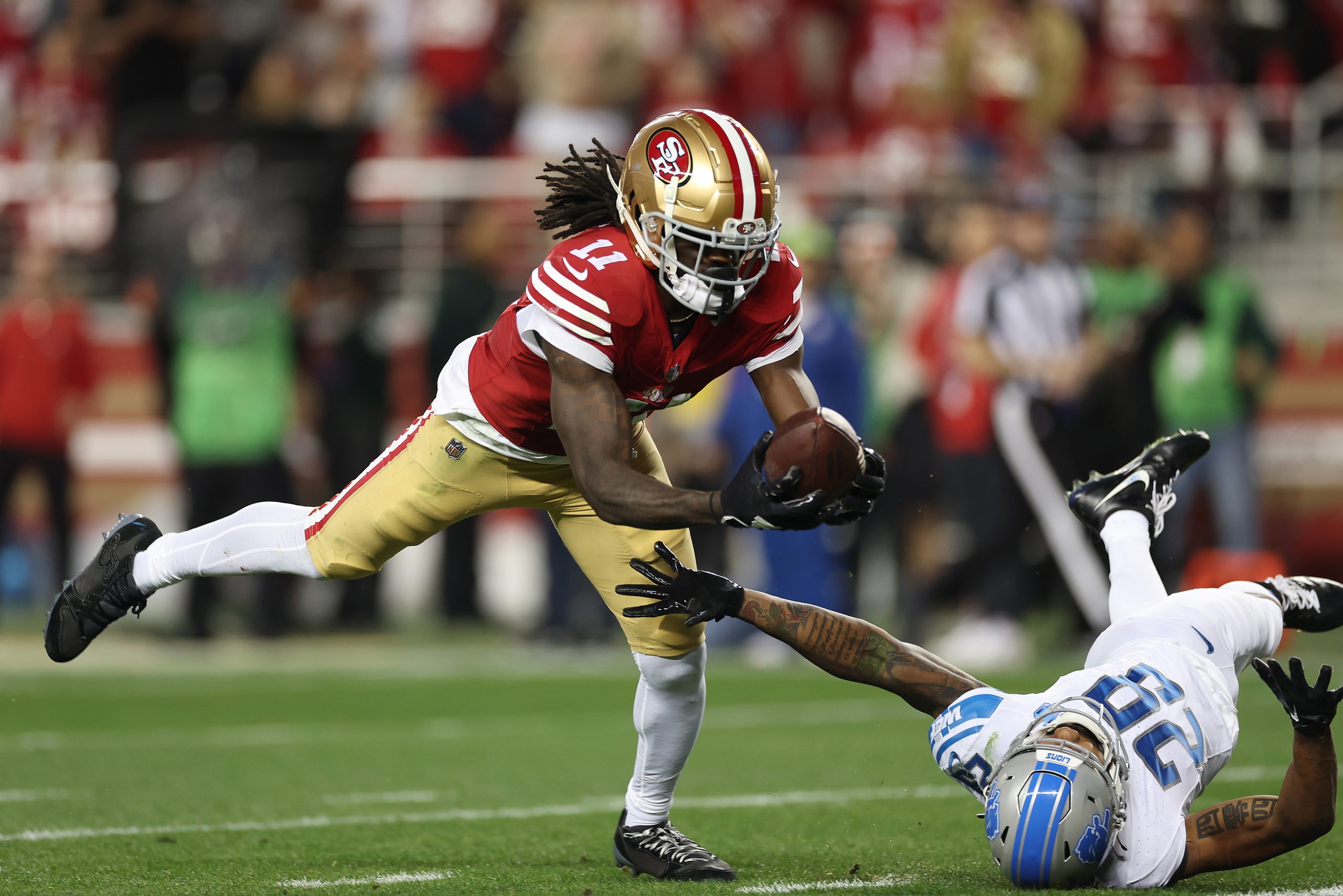 Brandon Aiyuk #11 of the San Francisco 49ers catches a pass that was tipped by Kindle Vildor #29 of...