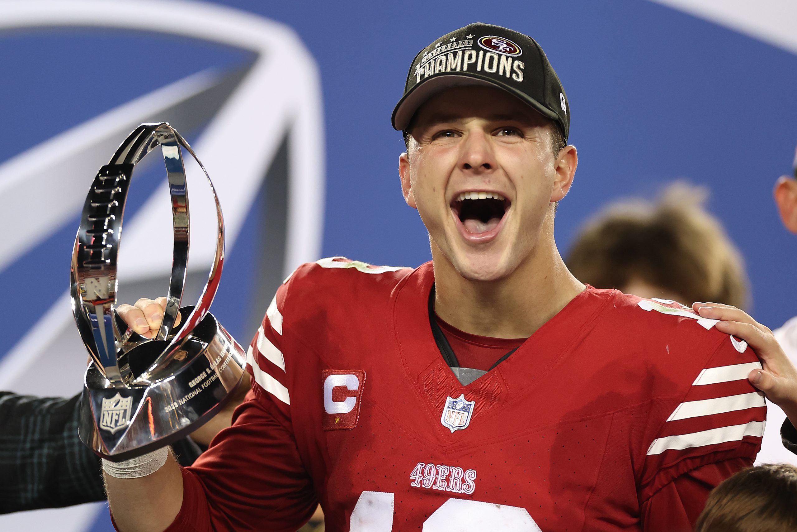Brock Purdy #13 of the San Francisco 49ers reacts as he holds the George Halas Trophy after defeati...