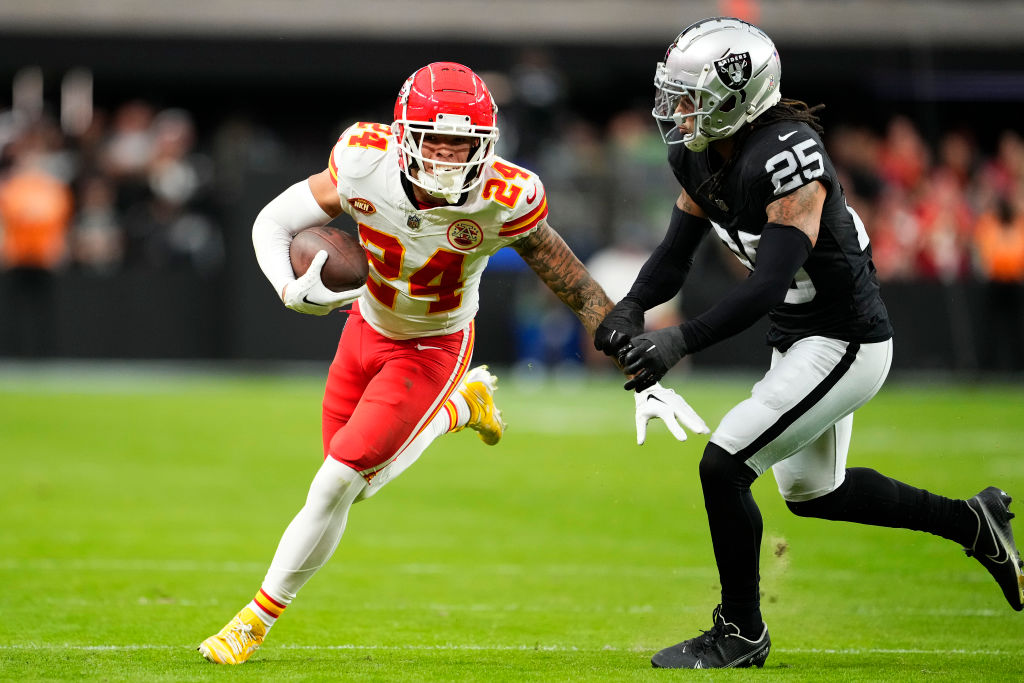 Skyy Moore #24 of the Kansas City Chiefs runs with the ball as Tre'von Moehrig #25 of the Las Vegas...