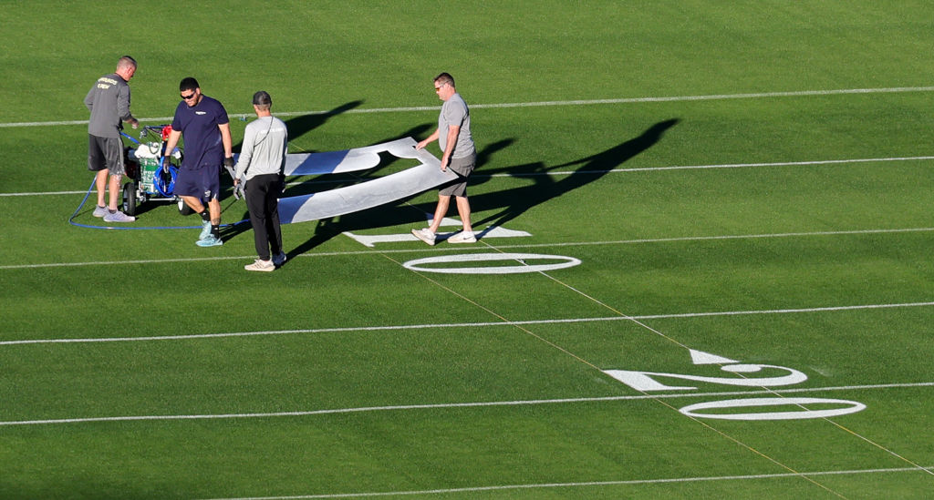Workers paint numbers on the field outside of Allegiant Stadium as crews get ready for Super Bowl L...