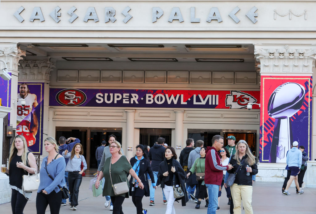 Visitors walk in front of an entrance to Caesars Palace with Super Bowl LVIII signage displayed on ...