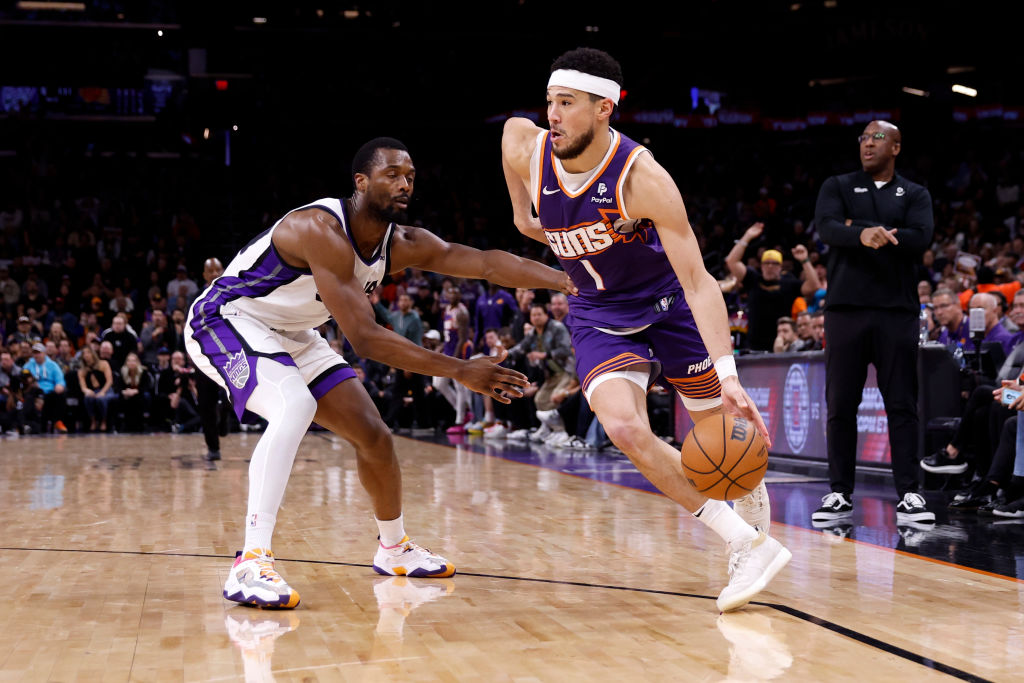 Devin Booker #1 of the Phoenix Suns drives against Harrison Barnes #40 of the Sacramento Kings duri...