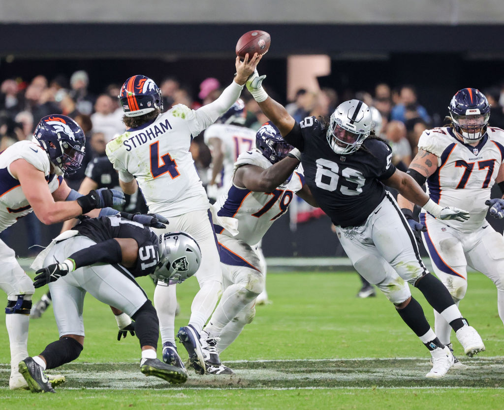 Quarterback Jarrett Stidham #4 of the Denver Broncos throws an interception under pressure from def...