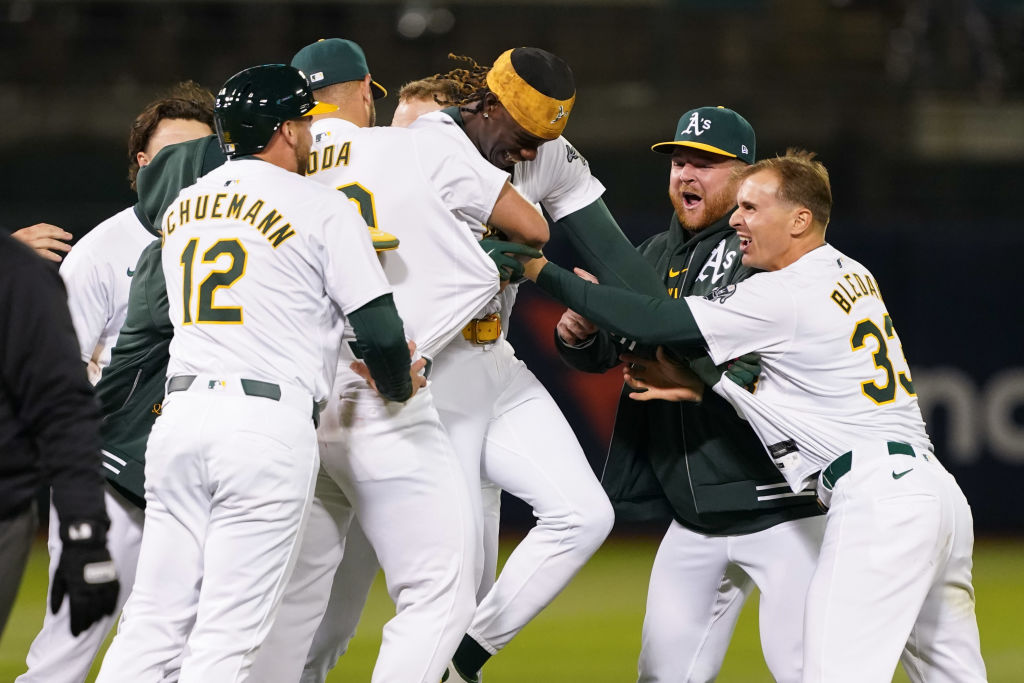 Lawrence Butler #4 of the Oakland Athletics celebrates with teammates after driving home the game w...