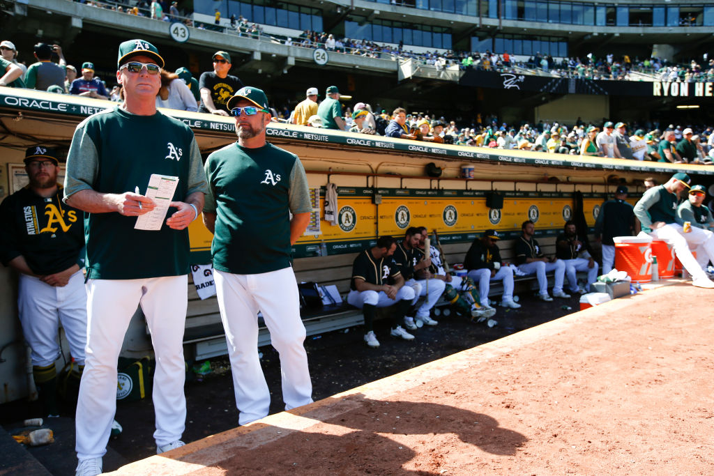 Manager Bob Melvin #6 and Bench Coach Mark Kotsay #7 of the Oakland Athletics stand in the dugout d...