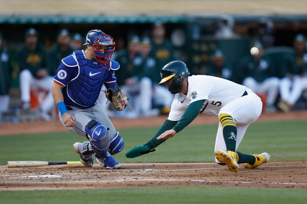 OAKLAND, CALIFORNIA - MAY 06: Base runner J.D. Davis #5 of the Oakland Athletics is hit by a throw ...