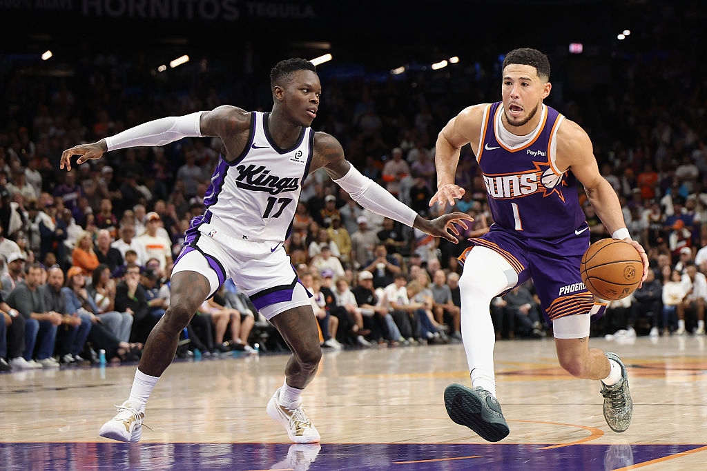PHOENIX, ARIZONA - OCTOBER 22: Devin Booker #1 of the Phoenix Suns handles the ball against Dennis ...